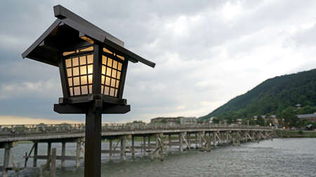 The traditional lamp, mountain, wooden bridge, rapid river in Japan Kyotoの写真素材