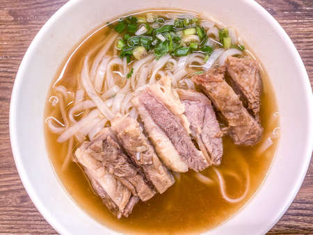 The bowl of Chinese food meat noodles on wooden tableの写真素材