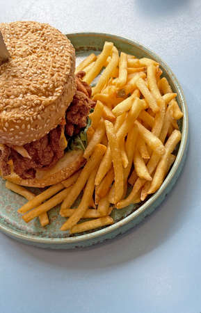 The vertical crispy chicken, sesame bread cheese burger with French fries on dishの写真素材