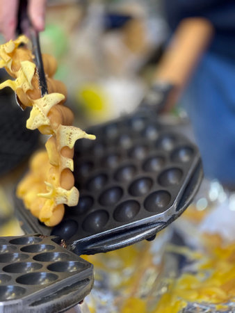 Vertical Hong Kong  traditional street dessert food bubble waffle egg with cooking panの写真素材