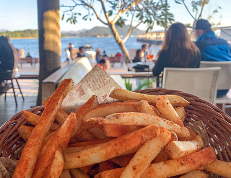 The basket of snack french fries, people in restaurant with sea view