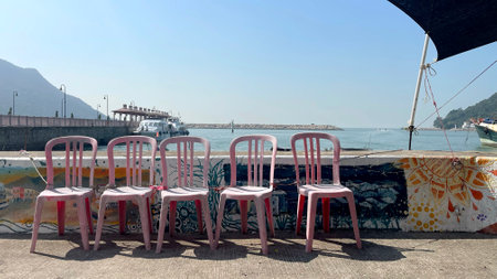 The Hong Kong outdoor recreational place, pink chairs, ships, pier in water harbourの写真素材