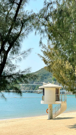 The vertical Hong Kong sand beach, lifeguard tower, water wave, mountain and treeの写真素材