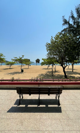 The vertical outdoor beach, sands, trees, water, garden wooden bench in Hong Kong Repulse Bayの写真素材