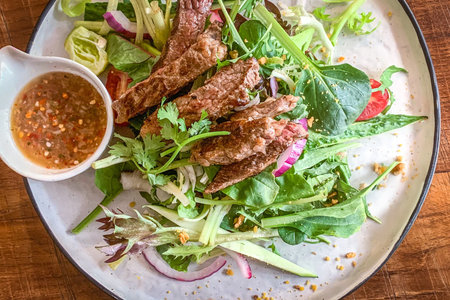 The roasted beef onion vegetable healthy salad on white dish and wooden tableの写真素材