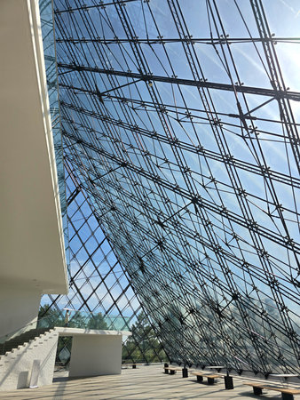 Modern architectural glass facade with geometric patterns against a bright blue sky