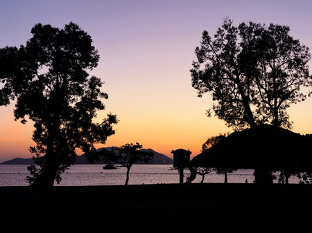 The sky transitions from deep purple to vibrant orange as the sun dips below the horizon, casting...