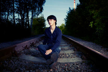 Moody young man acting his emotions and assuming depression and suicide ideas on outdoor location when posing for illustration photos.の写真素材