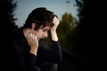 Moody young man acting his emotions and heartsickness on outdoor location when posing for illustration photos.の写真素材