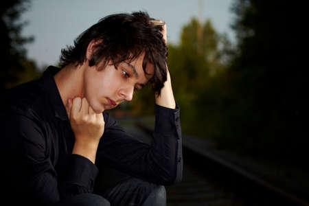 Moody young man acting his emotions and heartsickness on outdoor location when posing for illustration photos.の写真素材