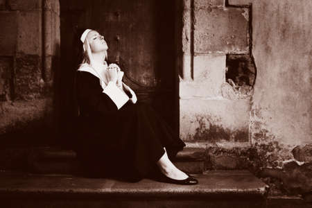 Nice girl posing like a nun sitting by church in Prague for religion style photos.の写真素材