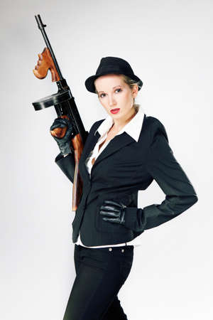 Mafia style fashion studio portrait - nice young woman posing with \\\"Tommy\\\" gun for figure and portrait photos in retro criminal style.の写真素材