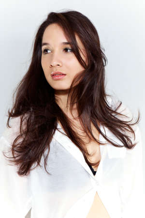 Cross-breed Euro/Asian long hair brunette girl posing in studio for portraits in several dress styles.の写真素材