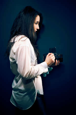Cross-breed long hair Euro/Asian brunette girl posing like a photographer with classic camera in studio.の写真素材