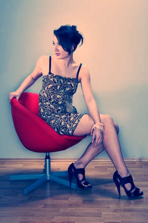 Cross-breed Asian/Euro long hair brunette girl sitting in red chair.の写真素材