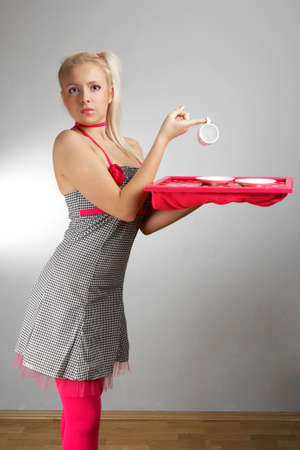 Young woman in retro style of fashion doll - housewife on interior location posing in various dresses.の写真素材