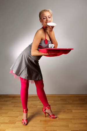 Young woman in retro style of fashion doll - housewife on interior location posing in various dresses.の写真素材