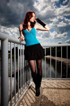 Nice redhair lady posing in summer light on outdoor location - river floodgate in several dress styles.の写真素材