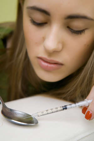 Drugs - young woman posing as a drug consumer on illustration photos with syringeの写真素材