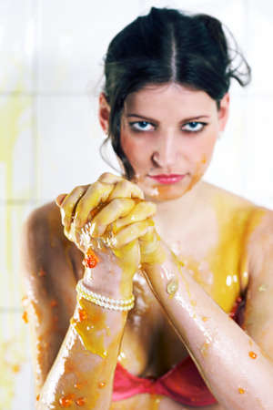 Young woman playing with melted Jelly in white tile roomの写真素材