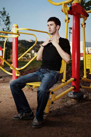 Outdoor workout - young man posing on location of open air fitness.