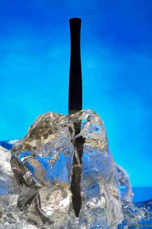 Plastic hypodermic frozen in ice block on the blue の写真素材