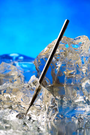 Plastic hypodermic frozen in ice block on the blue の写真素材