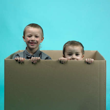 Children in studio portrait posing in large paper boxの写真素材
