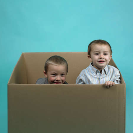 Children in studio portrait posing in large paper boxの写真素材