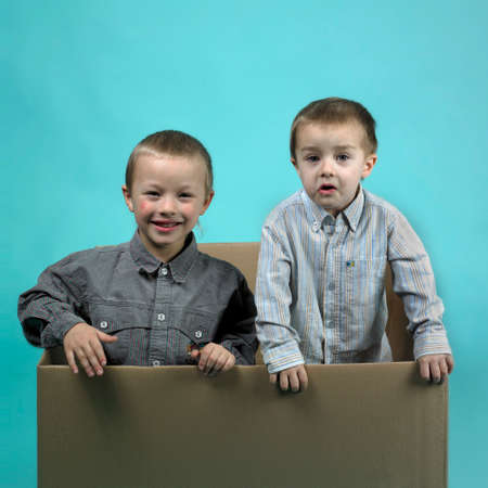 Children in studio portrait posing in large paper boxの写真素材