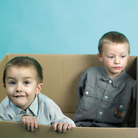 Children in studio portrait posing in large paper boxの写真素材