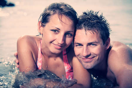 Young couple relaxing at beach in Italian resort Caorle bathing in sea water and summer sun.の写真素材