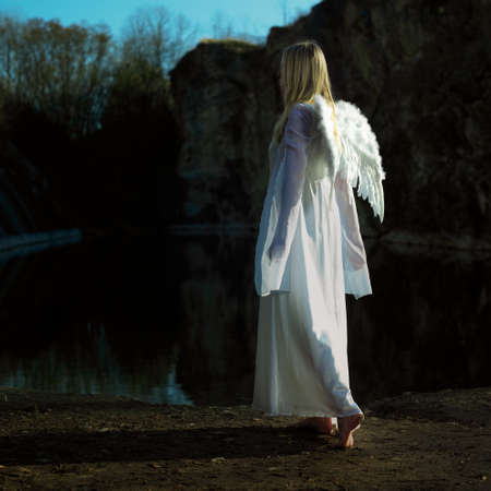 Angels on Earth! Lady posing with angel wings outdoor in nature by the lakeの写真素材