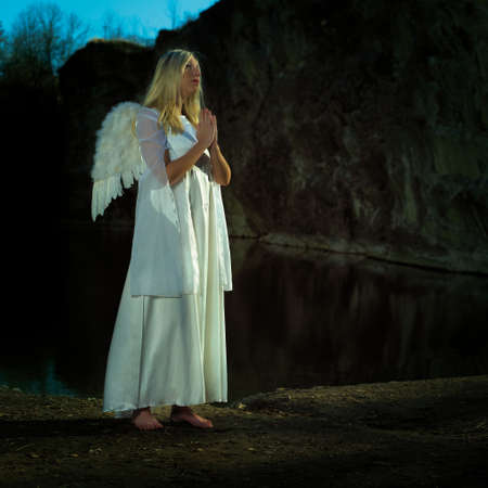 Angels on Earth! Lady posing with angel wings outdoor in nature by the lakeの写真素材