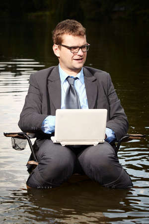 Crazy businessman in suit working in riverの写真素材