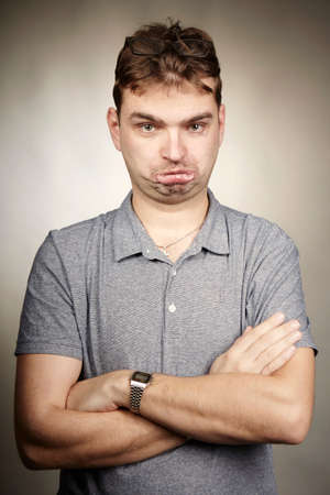 Angry adult man make faces in studioの写真素材