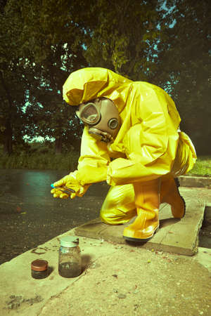 Man in chemical protective suit collecting samples of bad water contaminationの写真素材