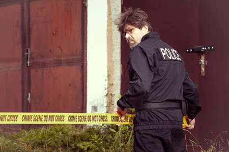 Police man working with barrier tape in city terrainの写真素材