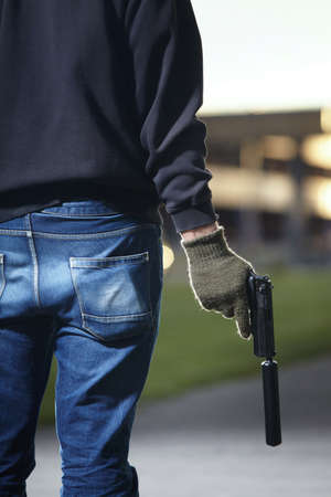 Man armed with pistol with silencer preparing for attack on public