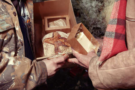 Two homeless older men celebrating christmas in park with giftsの写真素材