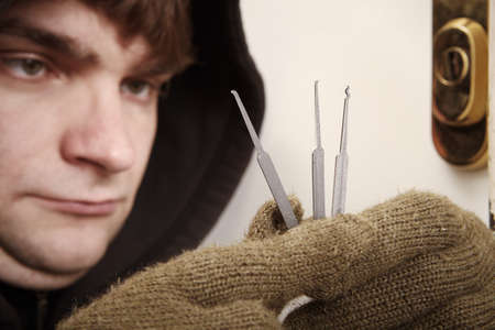 Thief in black hoodie breaking into property with plastic lockpick homemade toolsの写真素材