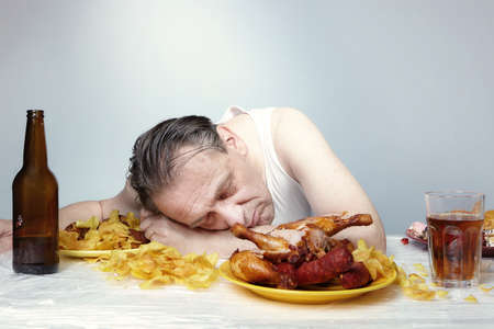 Aging man in a-shirt sleeping after eating a lot of junk food.