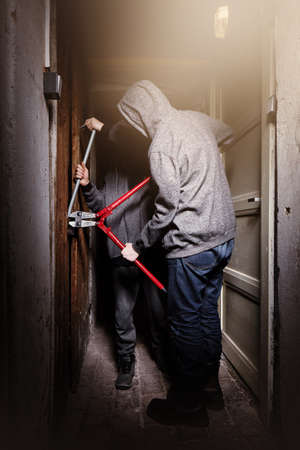 Two teenage burglars breaking in basement cellar with 30 inch bolt cutters