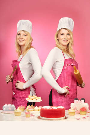 Nice blonde twins baking cakes posing with their sweetsの写真素材