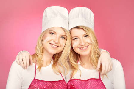 Nice blonde twins baking cakes posing with their sweetsの写真素材