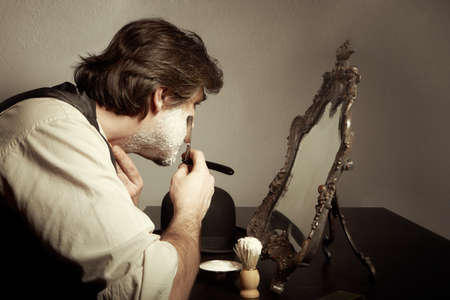 Prewar old style man shaving his beard with razor at homeの写真素材
