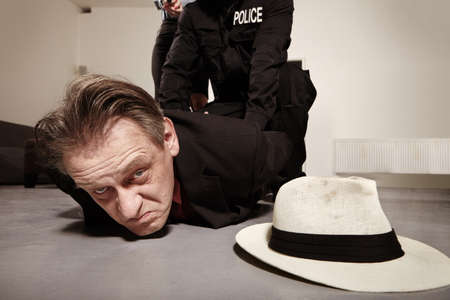 Criminal man in his hiding place is catched by police staff and bonded with handcuffsの写真素材