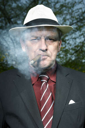 Bad evil man in mob style smoking cigar outdoorの写真素材