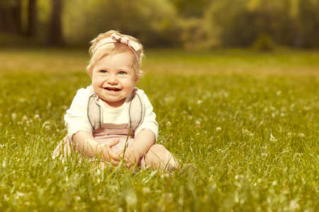 Ten months old girl baby posing in sunny summer park for portrait photoの写真素材