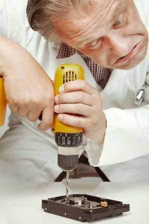Hard disc drive specialist erasing data from hard disc drive with drill